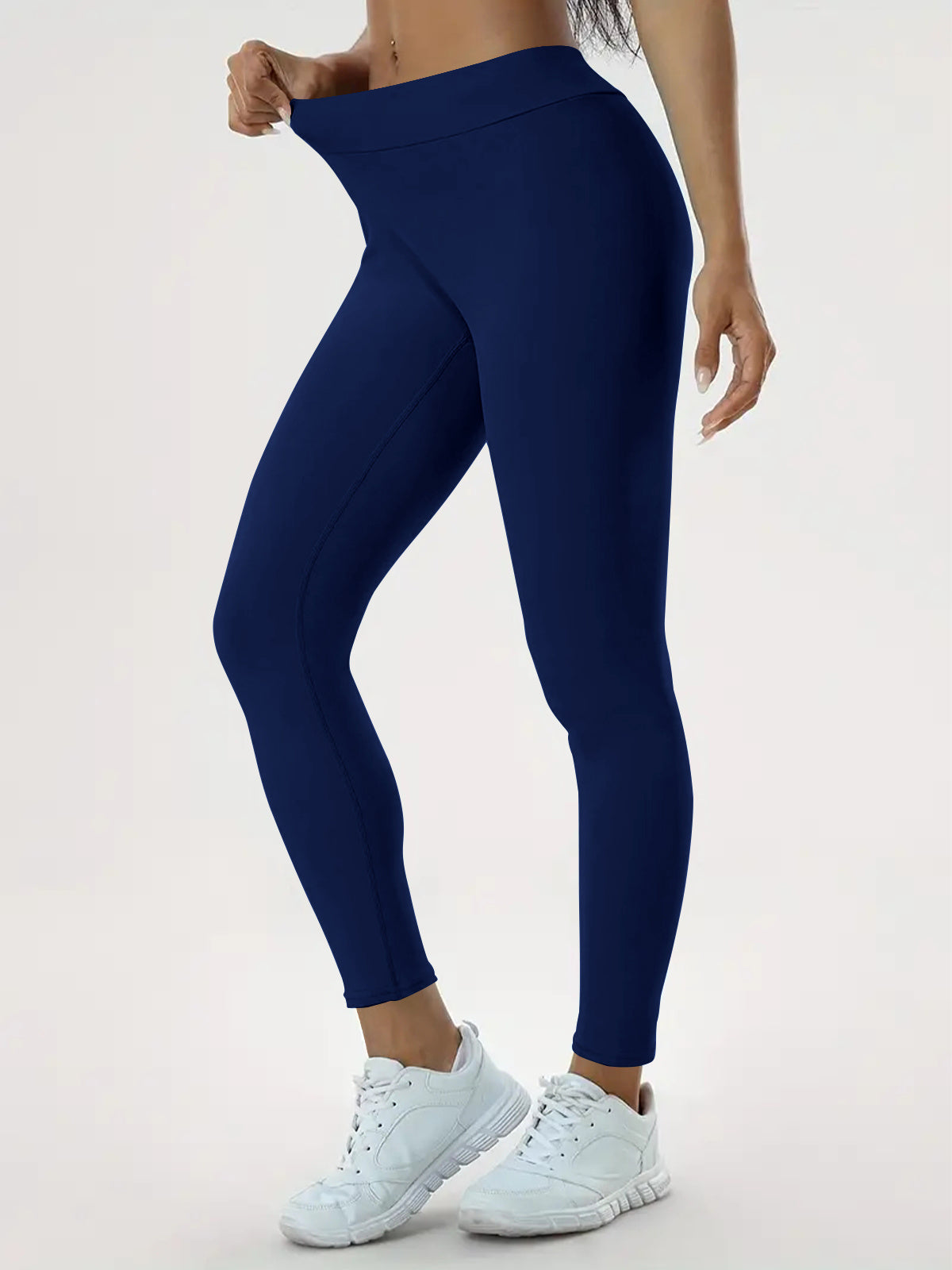 "Person wearing dark blue high-waisted leggings and white athletic shoes, showing the stretchiness and fit, ideal for yoga, fitness, and everyday wear."