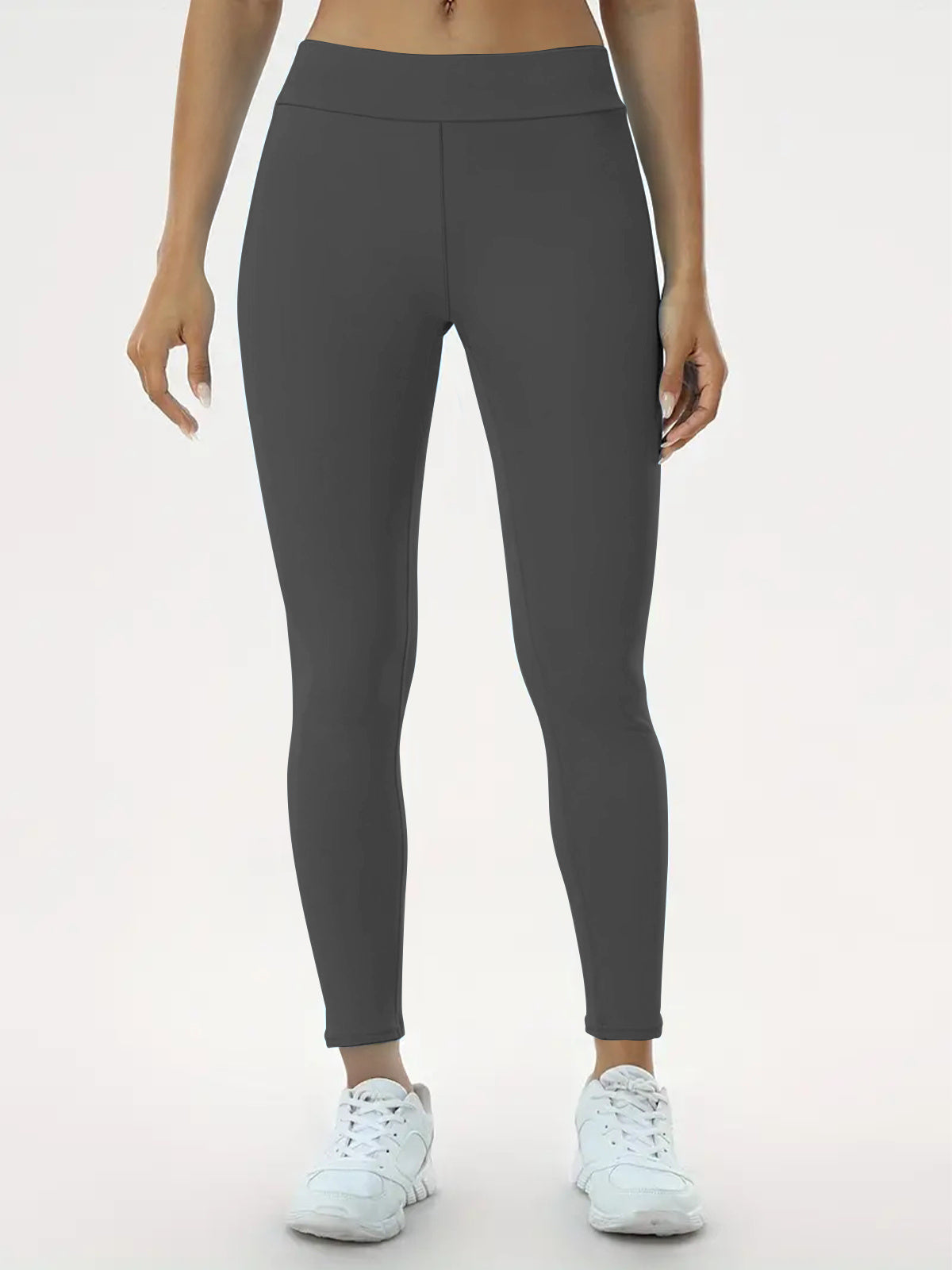 "Person wearing dark gray high-waisted ankle-length leggings paired with white athletic shoes, perfect for yoga, fitness, and everyday casual wear."