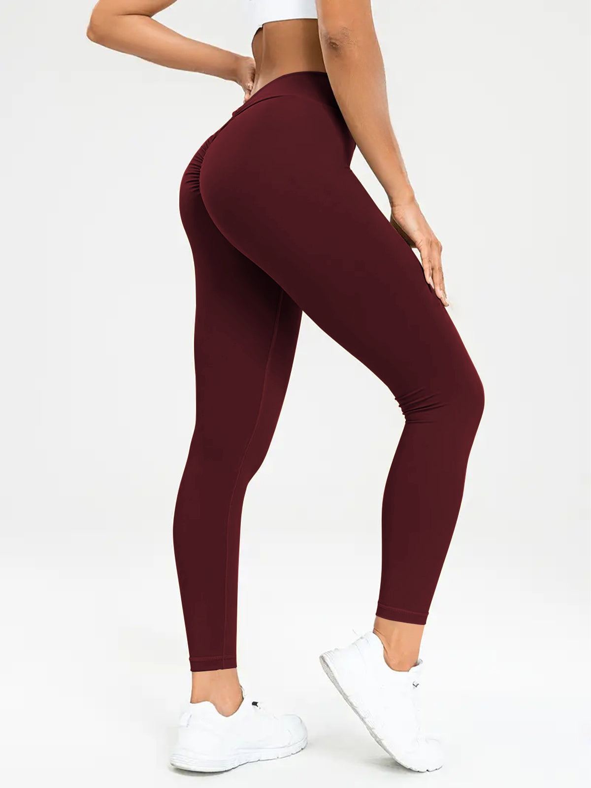 "Person wearing high-waisted maroon leggings with a scrunch detail at the back, paired with white athletic shoes and a white top, perfect for stylish and functional athletic wear."