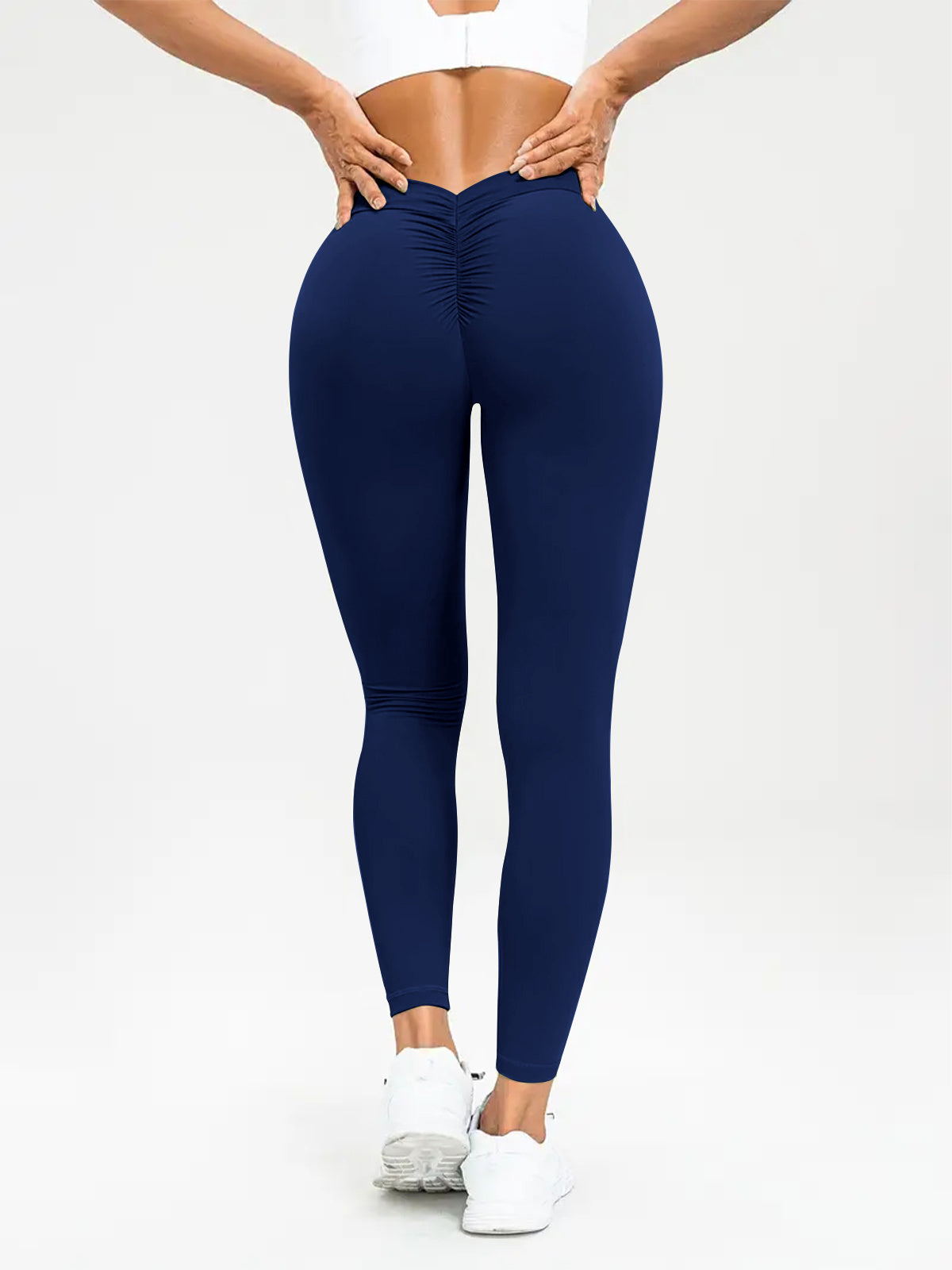 "Person wearing navy blue ruched leggings from the back, paired with white sneakers and a white top, showcasing the fit and style, perfect for workouts and casual wear."